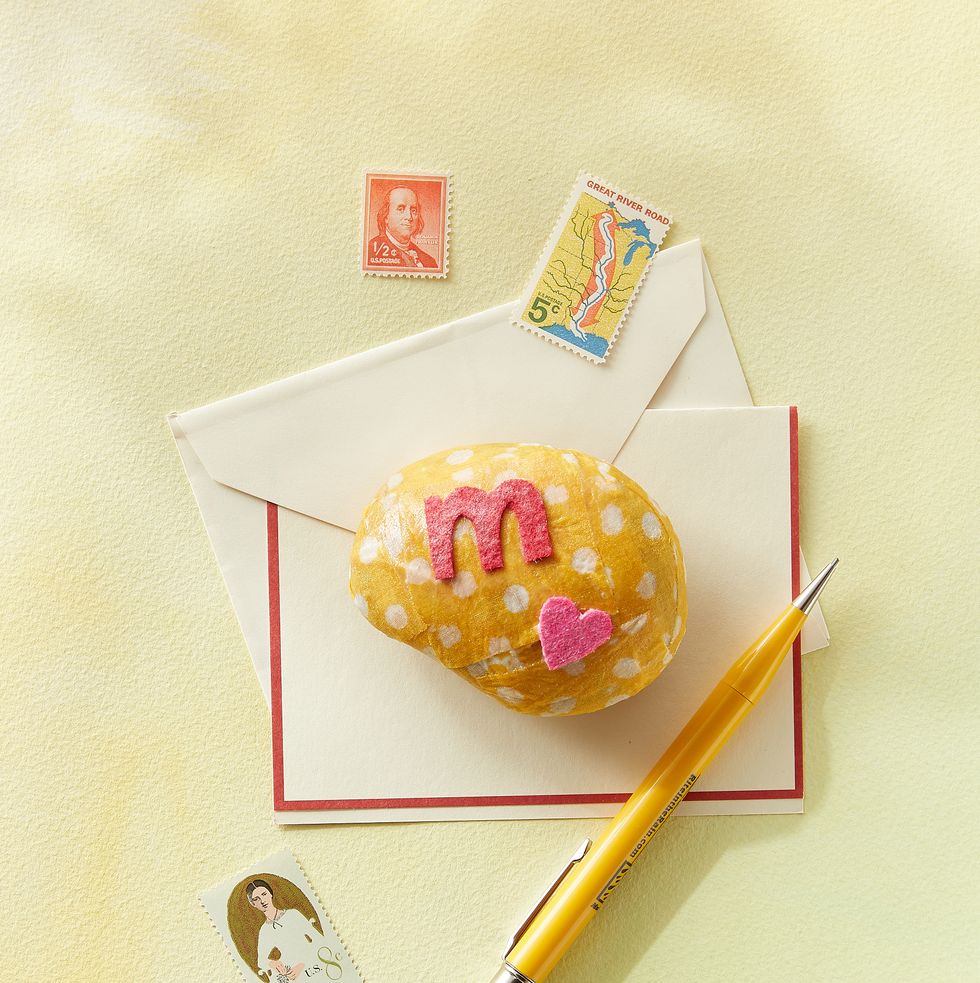 rock paper weight a kid might make for a mothers day craft, decoupaged in yellow fabric with white polka dots and decorated with a pink felt heart and letter m