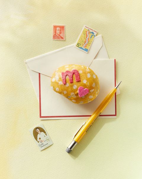 rock paper weight a kid might make for a mothers day craft, decoupaged in yellow fabric with white polka dots and decorated with a pink felt heart and letter m