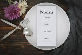 paper with menu on dining plate over rustic wood