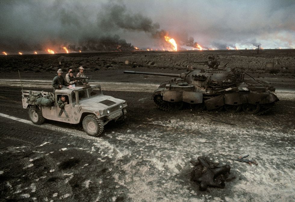 Een Amerikaanse patrouille nadert een verwoeste Iraakse tank en een verkoold lichaam Troepen van de Coalitie bevrijdden Koeweit op 27 februari 1991 Circa 50000 Iraakse soldaten waren gesneuveld en overal in het landschap van Koeweit waren nog de sporen van het conflict te zien olielekken branden en tanksporen