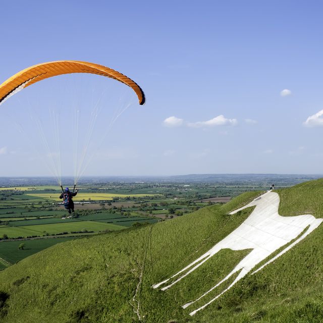a person parachuting on a grassy hill