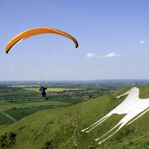 a person parachuting on a grassy hill