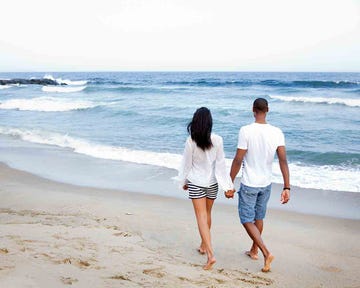 pareja caminando de la mano por la orilla del mar