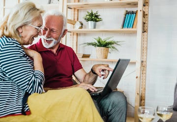 una pareja de ancianos con un ordenador portátil en el salón