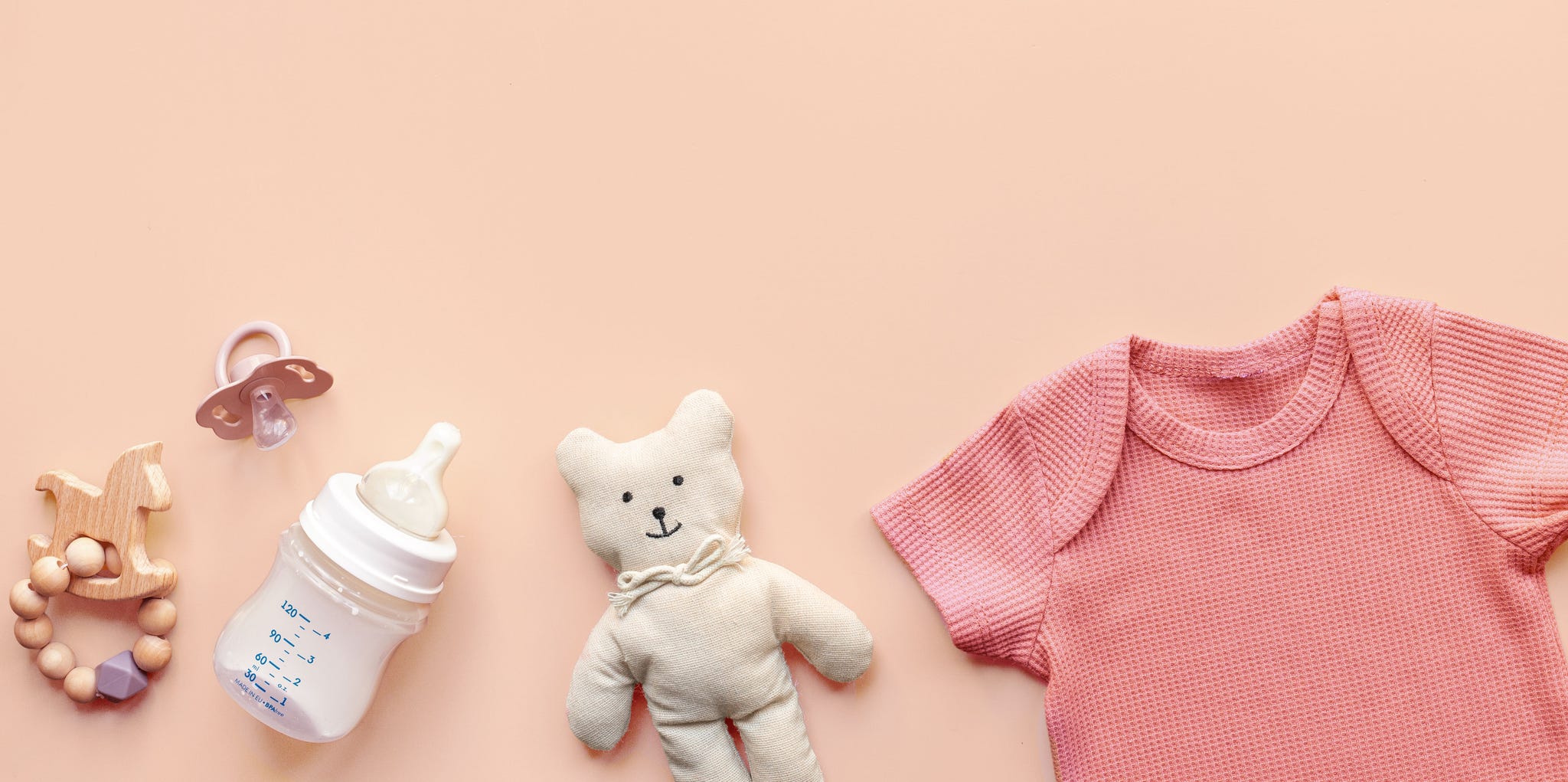 Flat lay with beige baby bodysuit and eco friendly toys, top view. Newborn background flat lay with beige baby bodysuit and eco friendly toys, top view. newborn background.
