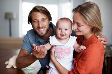 mom and dad holding happy baby girl