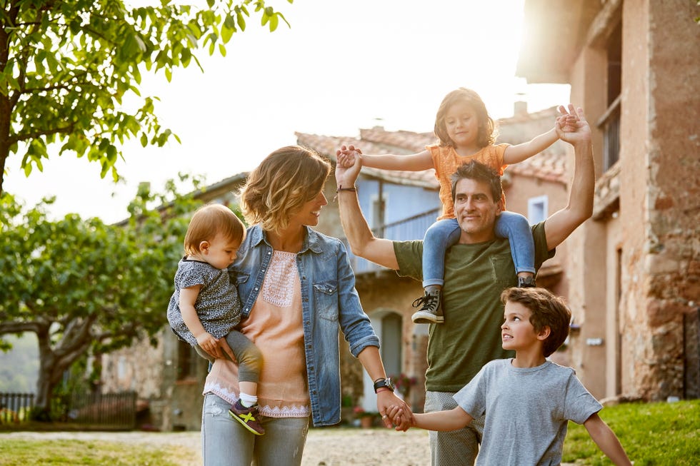 unos padres con tres hijos felices en el exterior de una vivienda con jardín