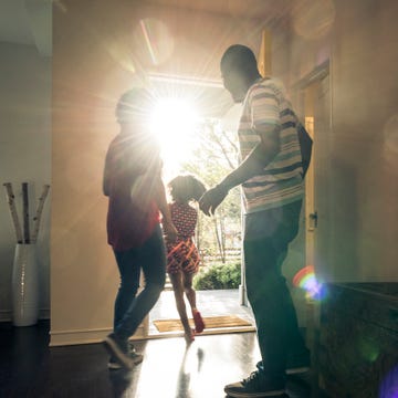 parents with daughter leaving the house in bright sunlight