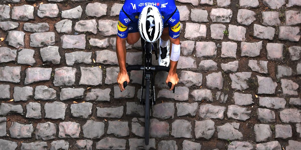 cyclist riding over cobblestones in paris roubaix race
