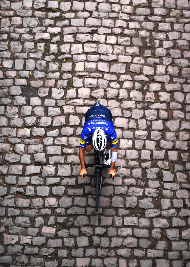 cyclist riding over cobblestones in paris roubaix race