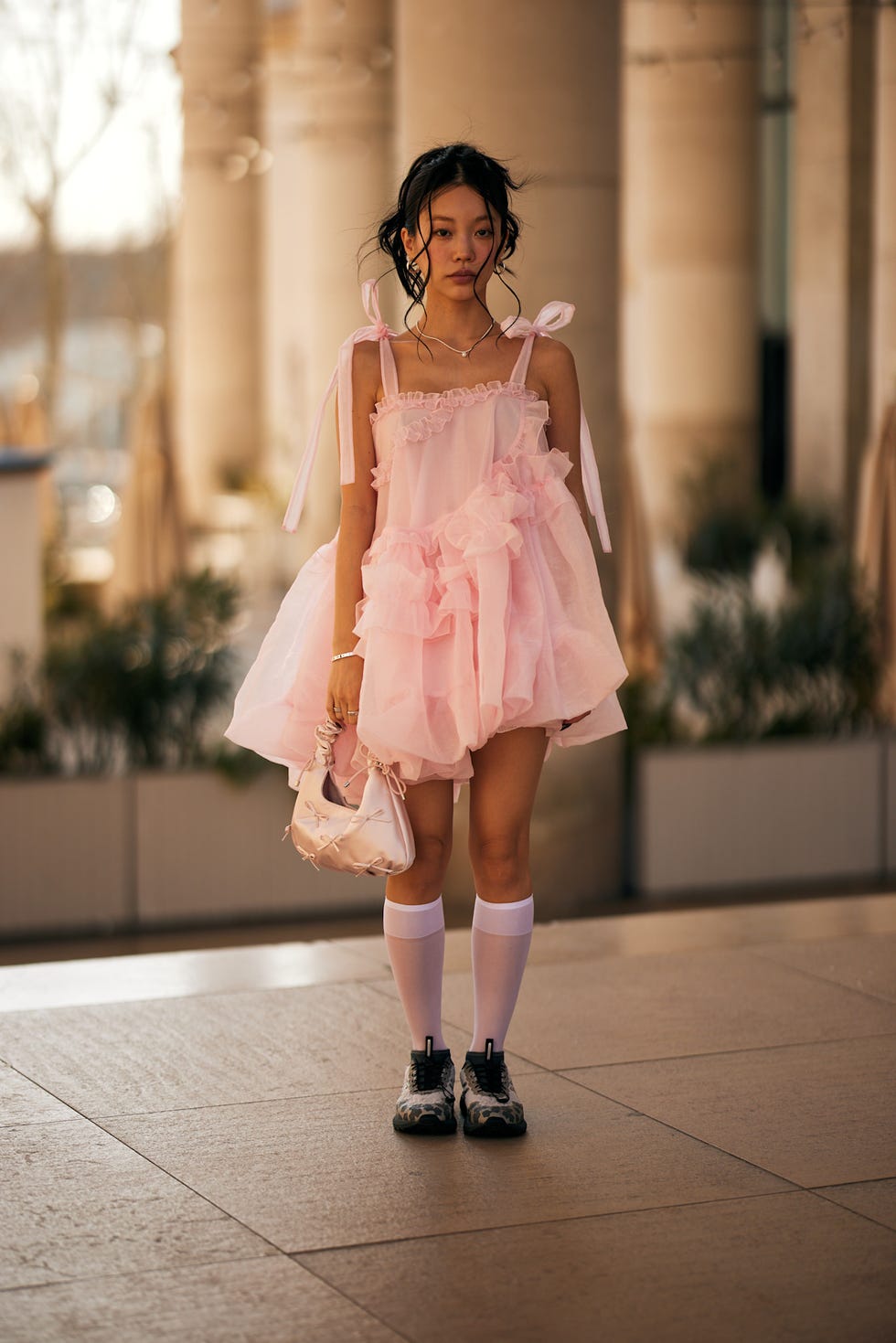 A person in a pink dress stands in an outdoor setting