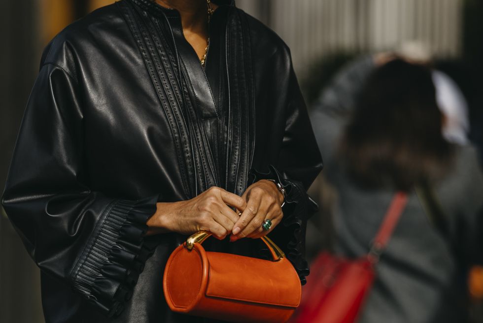 a person in a black coat carrying a purse