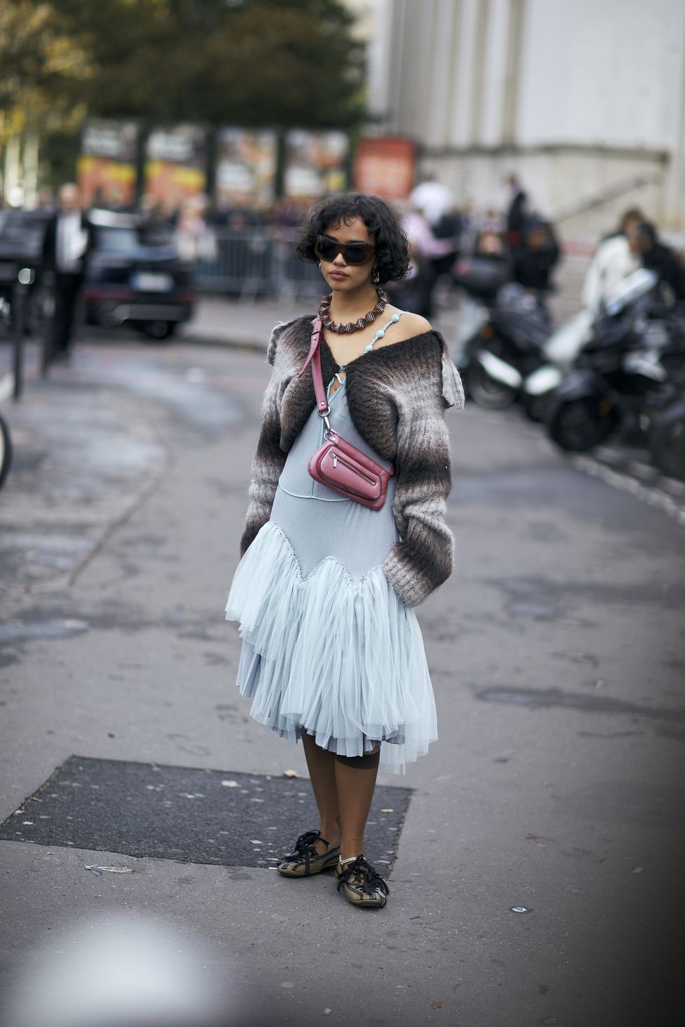 a woman in a fur coat and sunglasses on a sidewalk