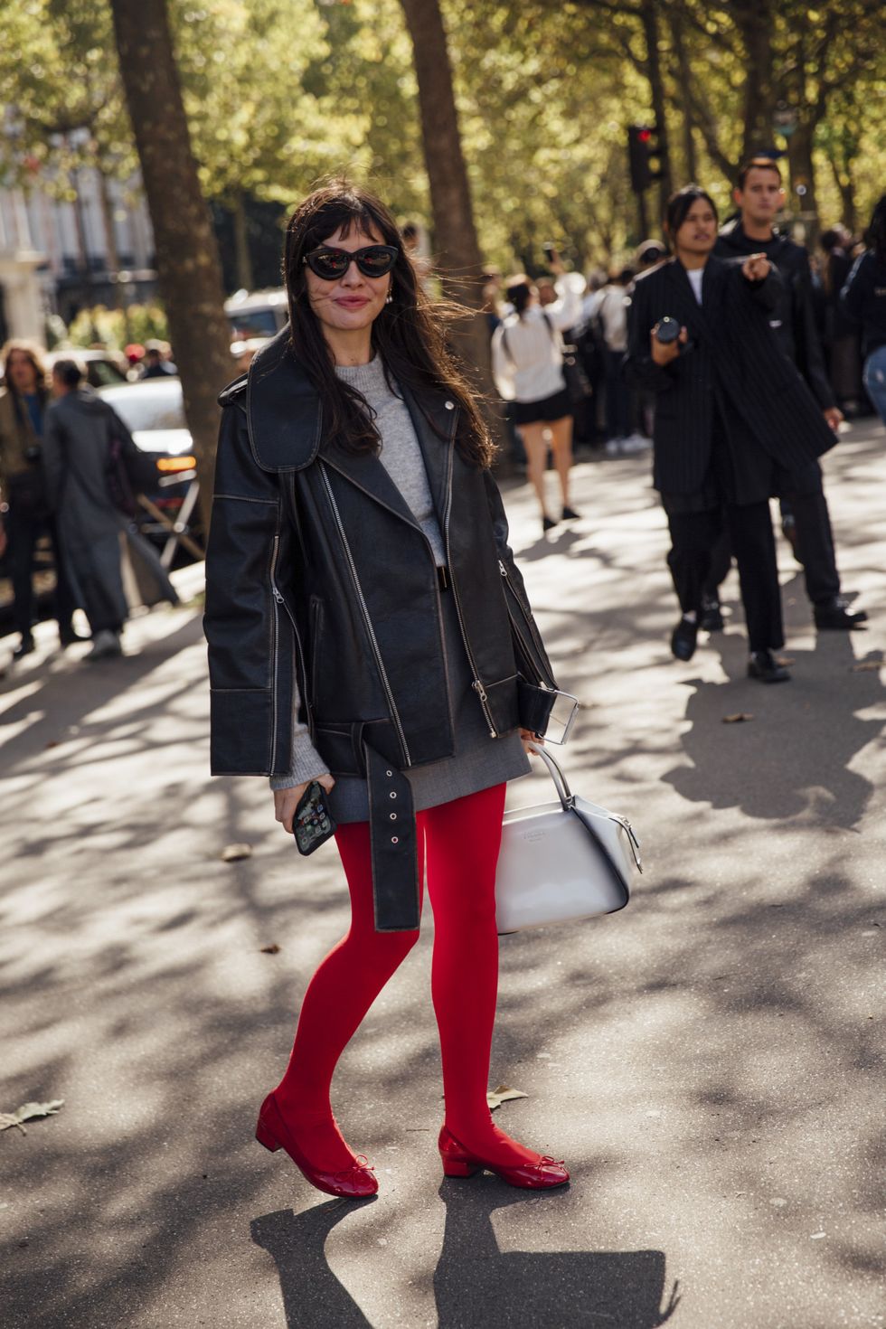 a woman in red pants and a black jacket with a purse