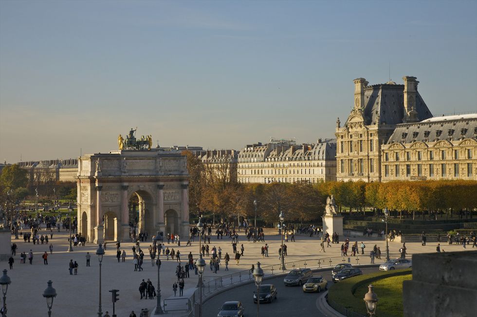 people moving through place du carrousel, paris, with the louvre at the right and arc du carrousel center