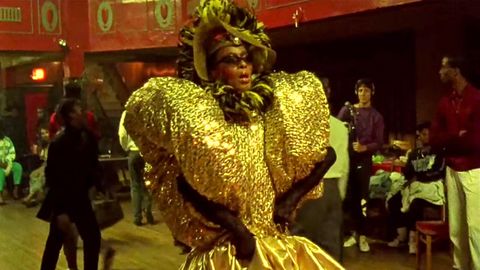 Pepper LaBeija walking the ballroom floor in a head-to-toe gold ensemble. 