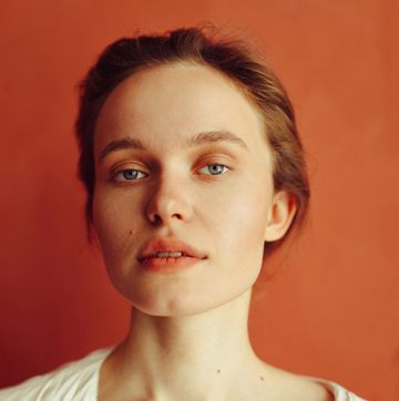portrait of young beautiful caucasian woman in white shirt posing against terracotta wall