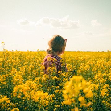 chica en el campo rodeada de flores