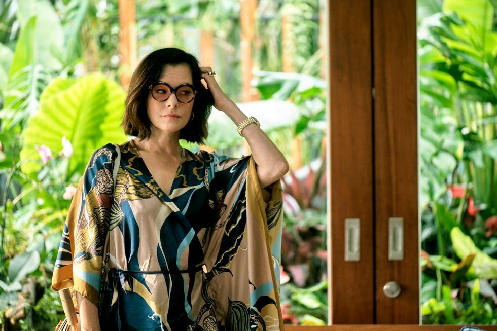 A person in a colorful garment stands amidst lush greenery