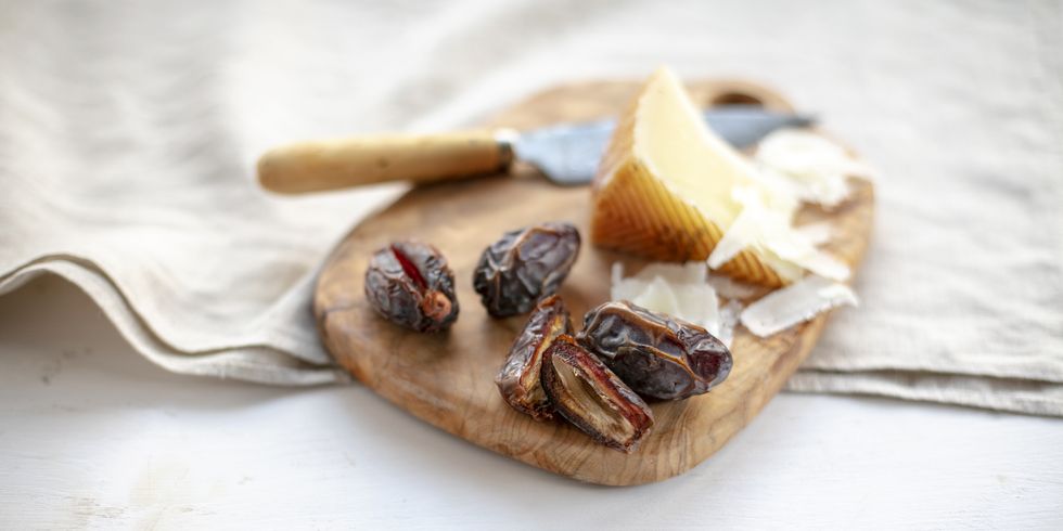parmesan cheese and date fruit on olive tree wooden board