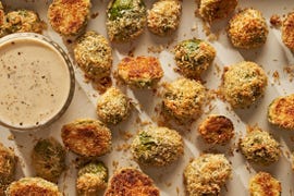 parmesan crusted brussels sprouts on a sheet pan next to a ramekin of caesar dressing