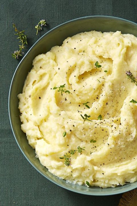 close up of a bowl of mashed potatoes with fresh herbs