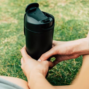 a part of a young woman holding a reusable plastic cup
