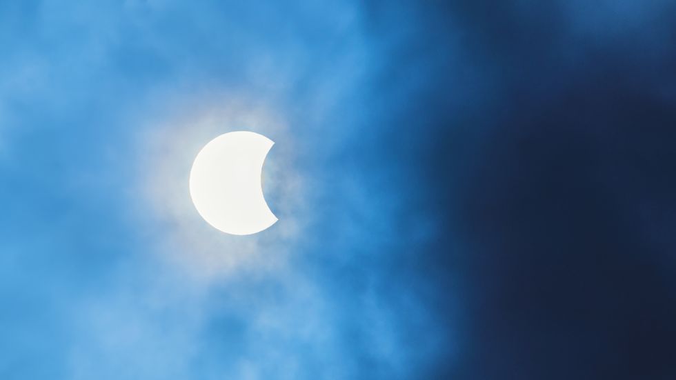 partial solar eclipse observed in costa rica, cloudy sky