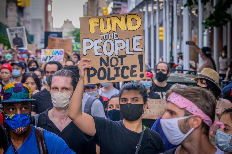 woman holding up sign that reads 'fund the people not police'