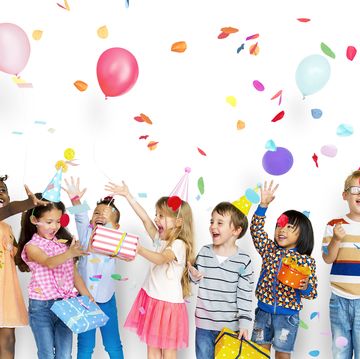 group of children celebrate party wearing party hats with balloons and confetti