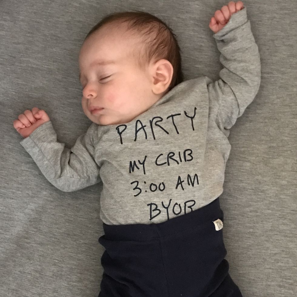baby lying in a crib with a bodysuit that says party in my crib 3 am bring your own bottle