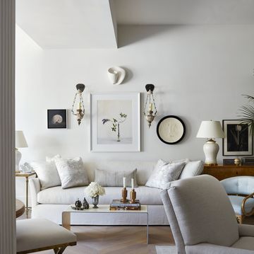 a pair of 19th century italian sconces flanks a still life painting by alec soth that hangs above a white sofa