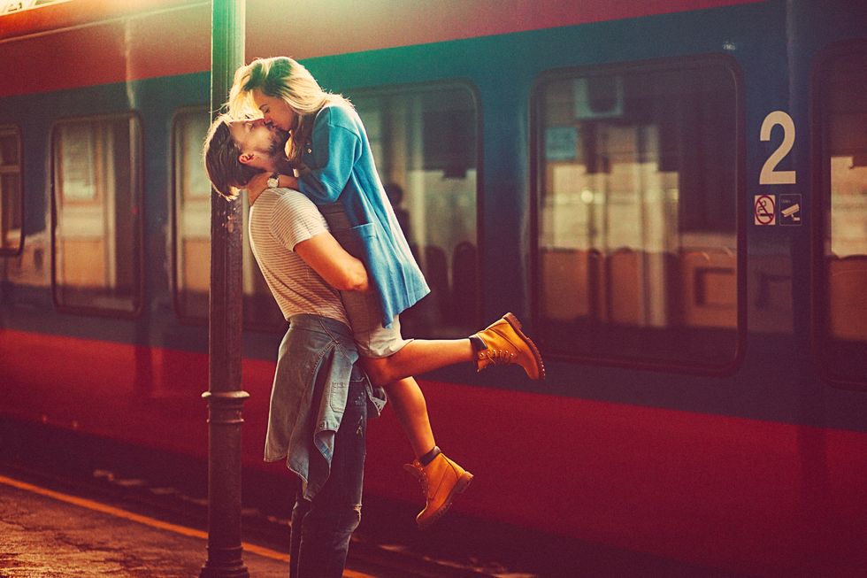 passionate young man and woman kissing beside the train at the railway station