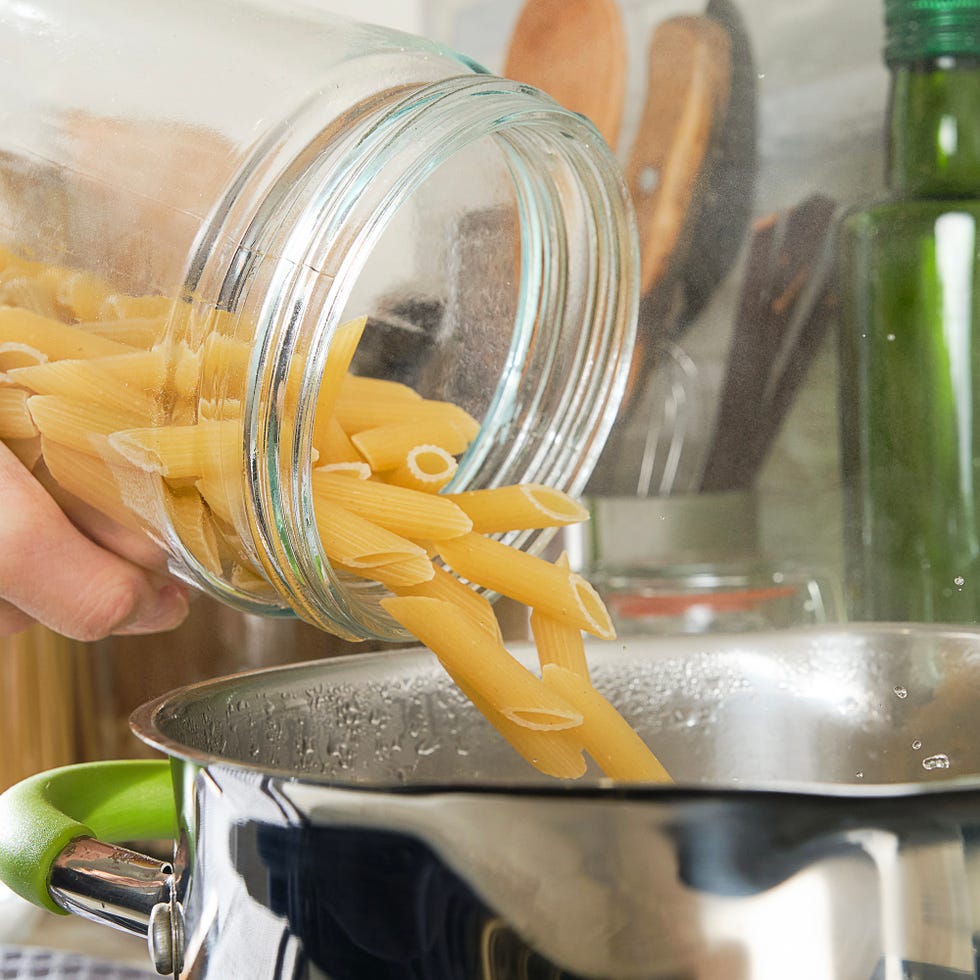 hands pouring pasting into boiling pot of water