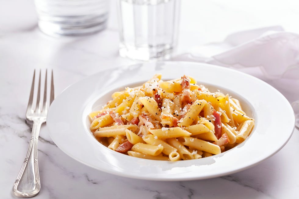 front view of penne carbonara on marble surface