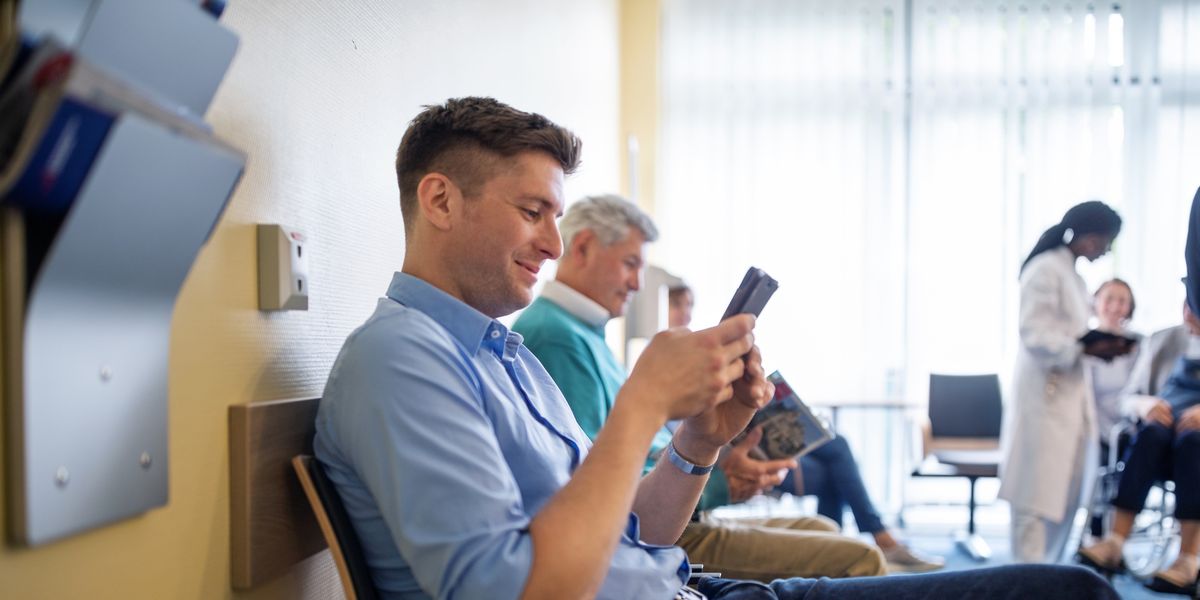 patients sitting in waiting room using mobile phone