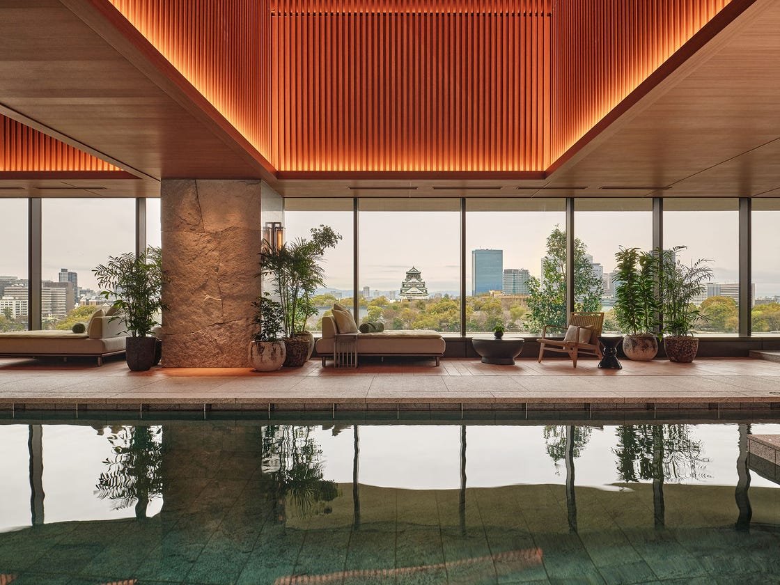 Indoor pool area with views of the city skyline and foliage