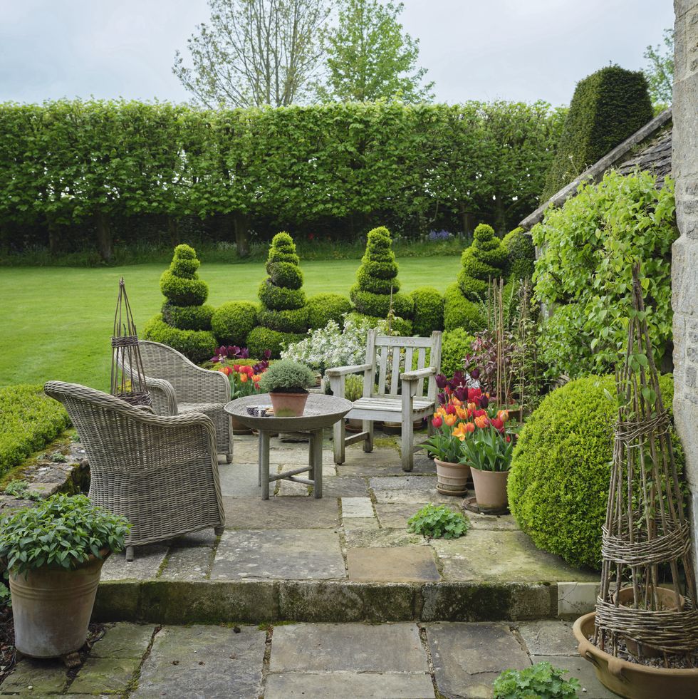 cotswolds home of oka cofounder sue jones charming spiral topiaries edge the sunny front terrace woven chairs
