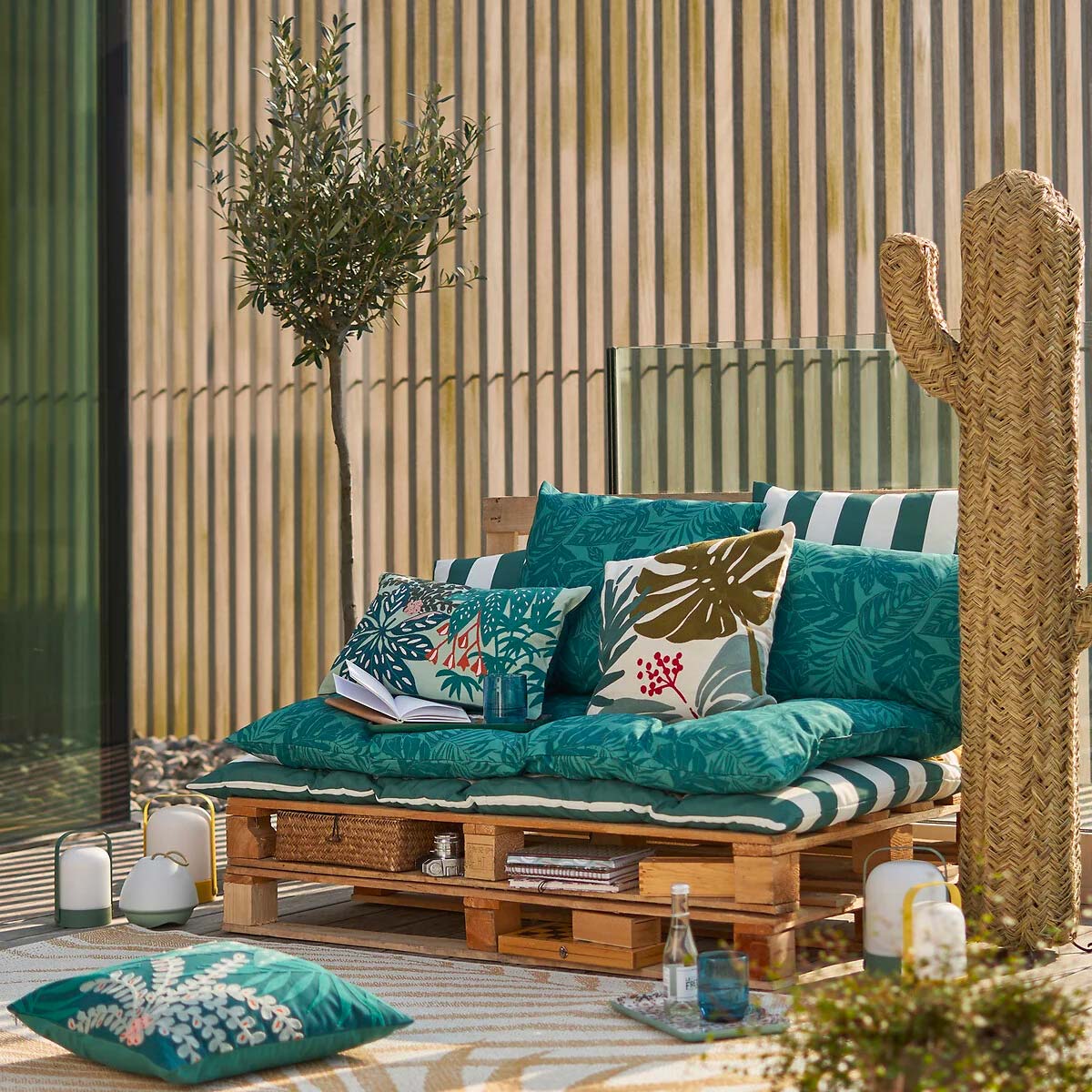 patio con sofá de palés y colchoneta con estampado verde