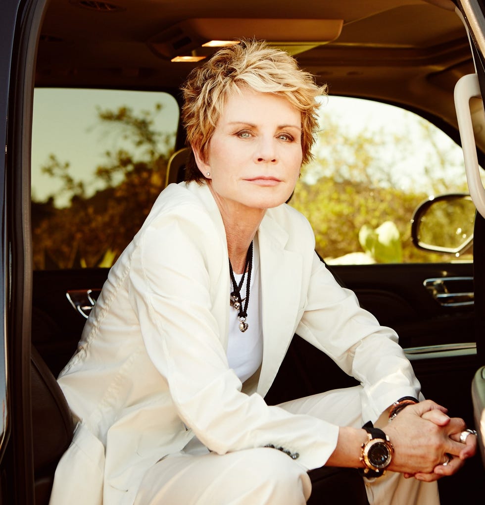 individual sitting in a luxury vehicle dressed in a stylish white attire with accessories