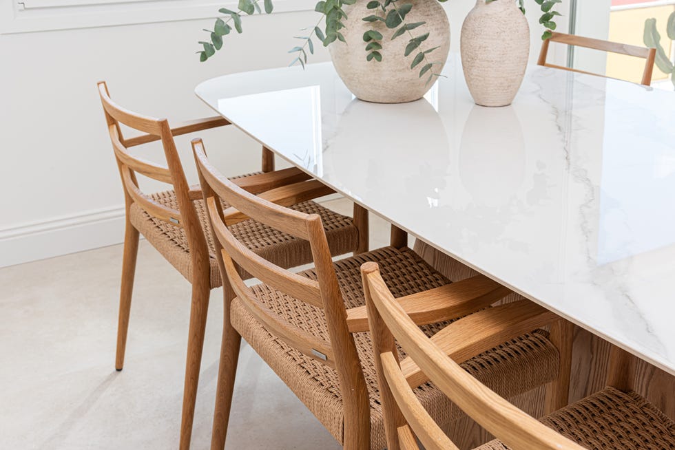 mesa de comedor con sobre de mármol y sillas de madera con asientos de cuerda