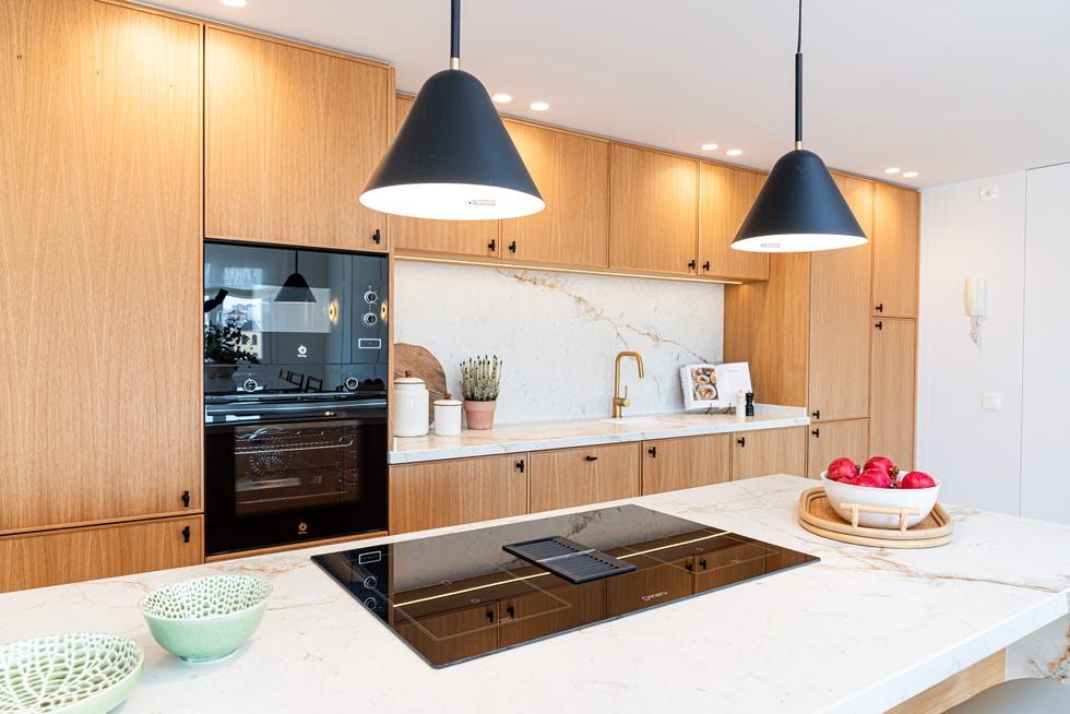 cocina con península, armarios de madera y revestimientos de mármol