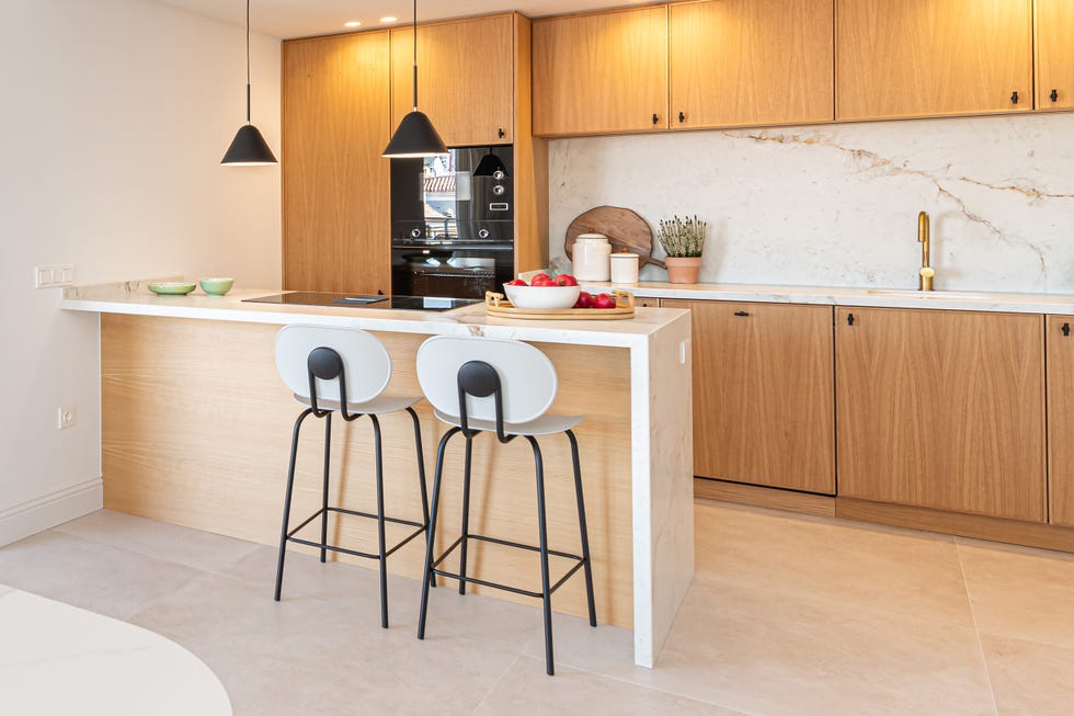 cocina con península, armarios de madera y revestimientos de mármol