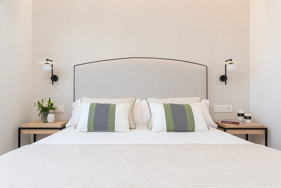 cabecero con ribeteado negro, apliques de pared y mesitas de noche de madera y metal negro
