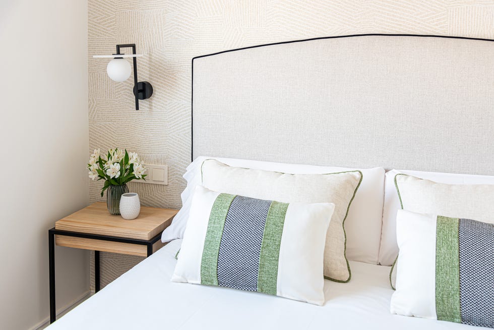 cabecero con ribeteado negro, apliques de pared y mesitas de noche de madera y metal negro