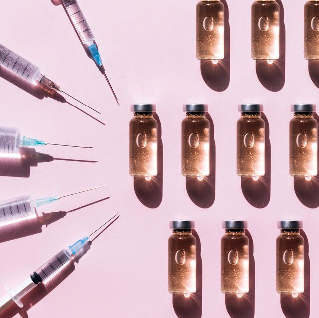 pattern made with set of clean syringes placed near vial of liquid drug near copy space on pink background with shadows and light reflections flat lay style