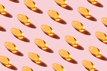 pattern of yellow fish oil capsules with omega 3 repetition on pink background