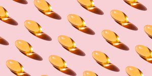 pattern of yellow fish oil capsules with omega 3 repetition on pink background