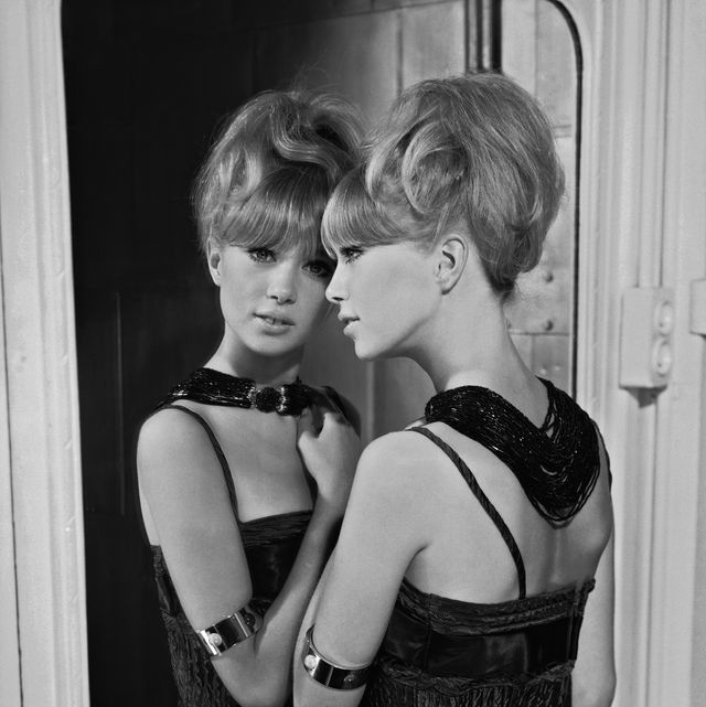 1964  patti boyd in un vestito da sera senza spalline ritratta da dietro mentre si specchia, i capelli sono acconciati su