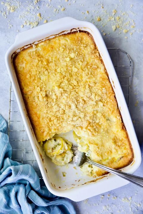 patty pan squash casserole with green chiles in a white rectangle baking dish with a serving fork